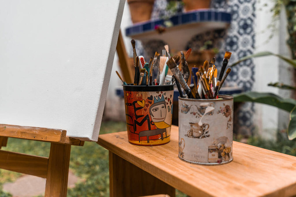 Pinceles en tarros y herramientas de pintor en un banco de madera - Foto, imagen