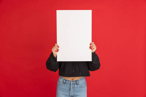 Πορτρέτο της Ασίας νεαρή κοπέλα με λευκό φύλλο χαρτιού απομονώνονται σε κόκκινο φόντο. - Φωτογραφία, εικόνα