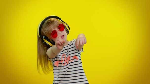 Funny playful blonde kid child girl listening music via headphones, dancing disco fooling having fun - Photo, Image