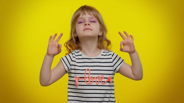 Child kid girl breathes deeply with mudra gesture, eyes closed, meditating, keep calm down, relax - Photo, Image