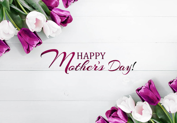 Komposition von Frühlingsblumen auf weißem Holzgrund. Viele weiße und lila Tulpen. Aufschrift Happy Mother 's Day. Werbeinhalte für den Muttertag. Flache Lage, Draufsicht, Nahaufnahme, Kopierraum - Foto, Bild