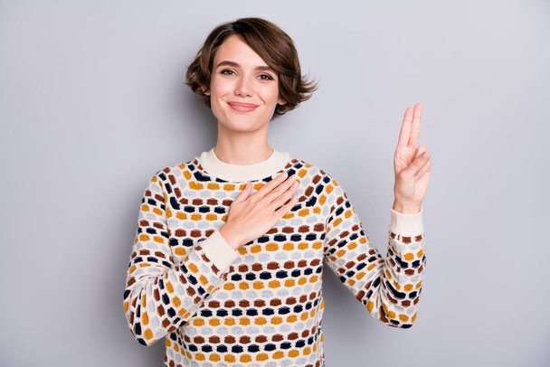 Portrait of pretty cheery peaceful brown-haired girl saying oath showing v-sign isolated over grey pastel color background - Foto, immagini