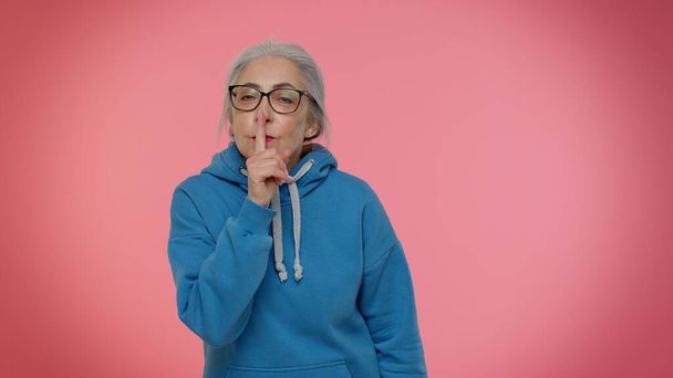 Oudere oma vrouw drukt index vinger tot lippen maakt stilte gebaar teken niet vertelt geheim - Foto, afbeelding