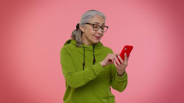 携帯電話を使用してシニアおばあちゃんの女性は、新しいポストを入力します,ミリ秒メッセージ,ブラウジング,ソーシャルネットワーク - 写真・画像