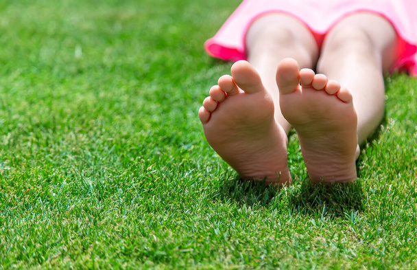 Die Füße eines Kindes auf dem Rasen im Gras. Selektiver Fokus. Kind. - Foto, Bild