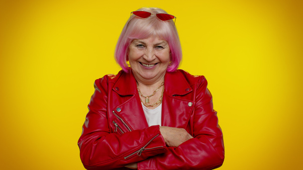 Vidám, elegáns, idősebb nagymama nő rózsaszín haj piros bőrdzsekiben mosolyog, a kamerába néz - Fotó, kép
