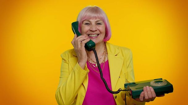 Senior stylish granny woman talking on wired vintage telephone of 80s, says hey you call me back - Photo, Image
