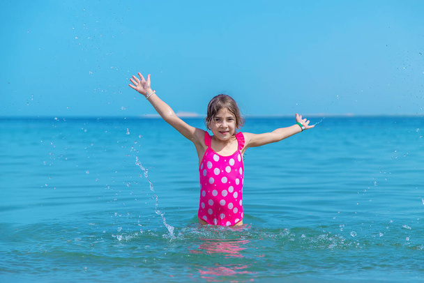 Das Kind macht Wasserspritzer auf dem Meer. Selektiver Fokus. Kind. - Foto, Bild