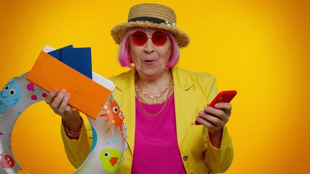 Старша жінка бабуся з мобільним телефоном святкування перемоги на курорті відпочинку квитки проходять
 - Фото, зображення