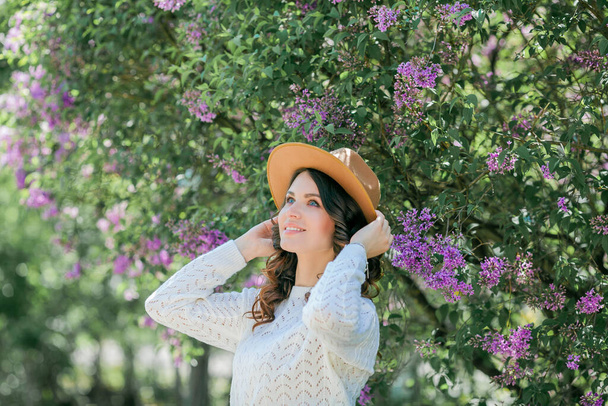Portrait of a beautiful young woman in a blooming lilac park. Purple flowers. Spring. - Photo, Image