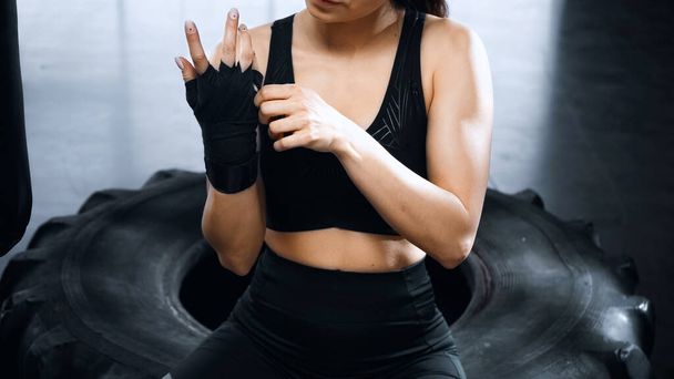 обрезанный вид молодой спортсменки, надевающей на руки боксерские бинты - Фото, изображение