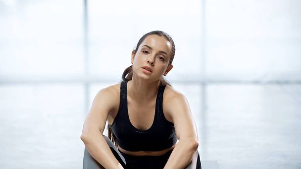 потная молодая спортсменка сидит во время отдыха в тренажерном зале  - Фото, изображение