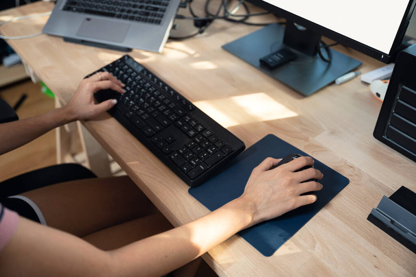 Vrouwelijke freelancer werkt met computer, typt toetsenbord en klikt op muis op houten bureau. werk vanuit huis concept - Foto, afbeelding
