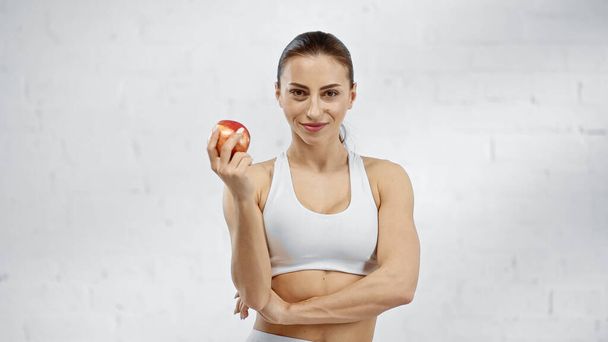 Smiling sportswoman holding fresh apple  - Fotó, kép