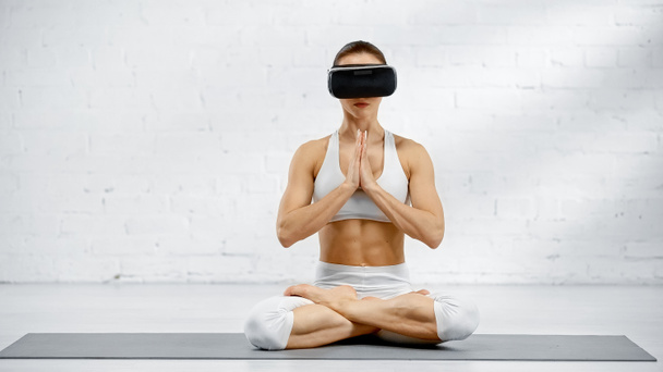 Jeune femme en vr casque assis dans la pose de yoga  - Photo, image