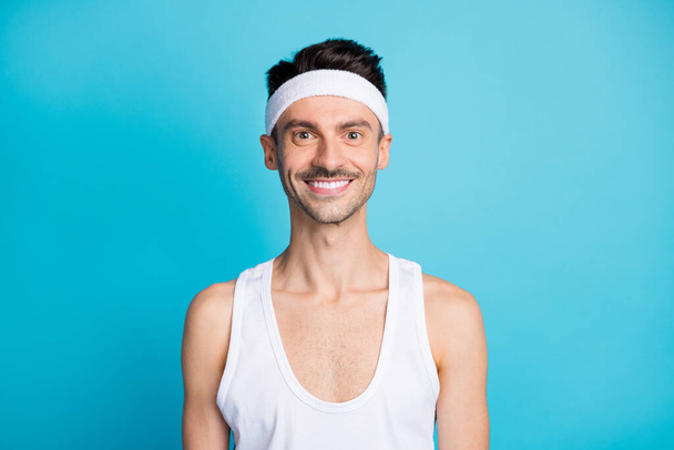 Retrato del aspecto deportivo positivo del hombre en la ropa de la cámara camiseta deportiva blanca aislada sobre fondo de color azul - Foto, imagen