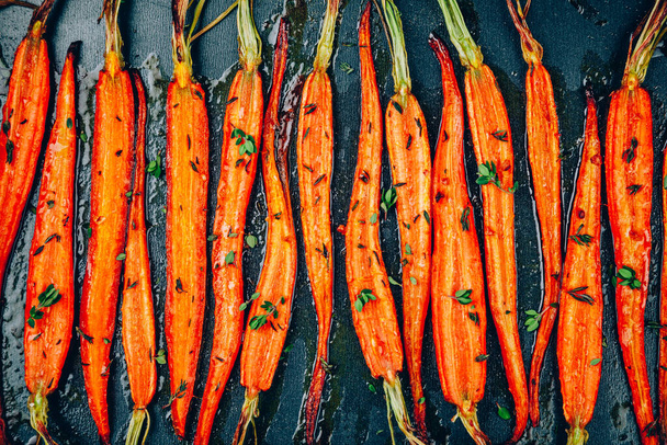 Roasted Carrots. Baked baby carrots with thyme in a black tray, top view - Φωτογραφία, εικόνα