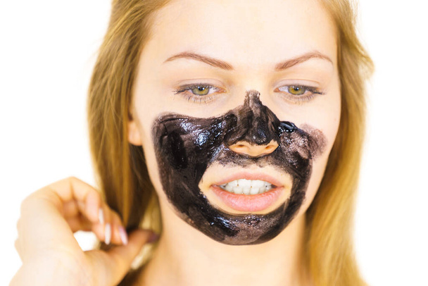Young woman applying carbo detox black mask to her face. Teen girl taking care of oily skin, cleaning the pores. Spa treatment. Skincare. - Foto, afbeelding
