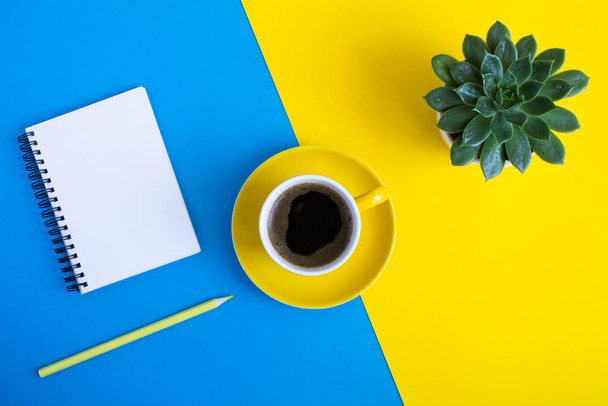 Top view of coffee cup, cactus, yellow pencil and notepad for writing  on the colored  background. Flat lay of workspace desk. Copy space. - Fotoğraf, Görsel