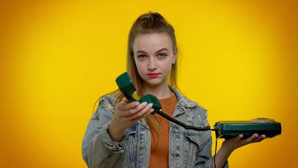 Cheerful teen girl secretary talking on wired vintage telephone of 80s, says hey you call me back - 写真・画像