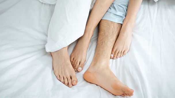 top view of barefoot couple lying on bed - Valokuva, kuva