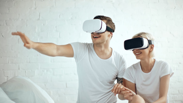 happy tattooed man and cheerful blonde woman in vr headsets  - Foto, Bild