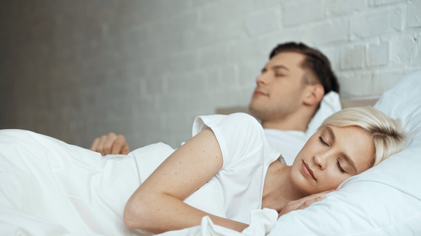 blonde woman sleeping in bed with man in blurred background  - Foto, Imagem