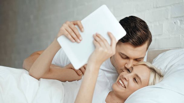 happy woman holding digital tablet and taking selfie with caring man  - Photo, Image