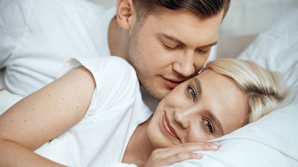 young man kissing cheek of happy blonde girlfriend  - Photo, Image