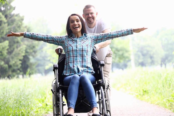 Chico lleva alegre mujer en silla de ruedas primer plano - Foto, imagen
