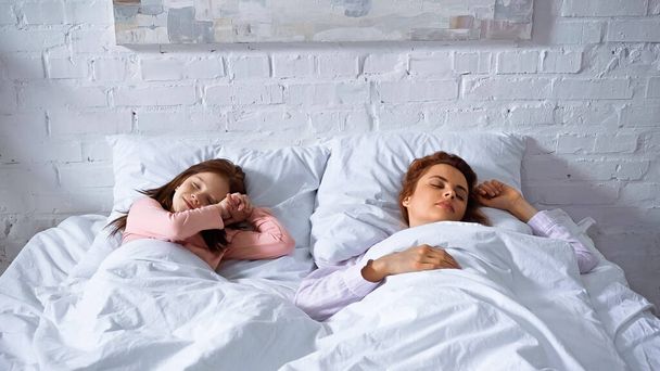Smiling kid and mother sleeping at home  - Foto, imagen