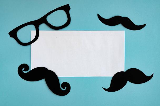 happy father day, composition of black mustache and glasses on blue background, greeting card with white sheet of paper and place for text - Photo, Image