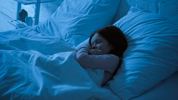 Preteen kid hugging blanket while sleeping on bed  - 写真・画像