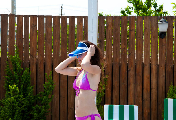 donna in costume da bagno viola con cappuccio in plastica nella calda giornata di sole, estate. - Foto, immagini
