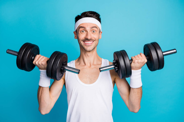 Photo of young sportsman happy positive smile bodybuilding arms dumbells isolated over blue color background - Φωτογραφία, εικόνα