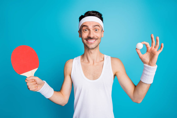 Photo of young sportsman happy positive smile play ping pong hold tennis ball raquete isolated over blue color background - Foto, afbeelding