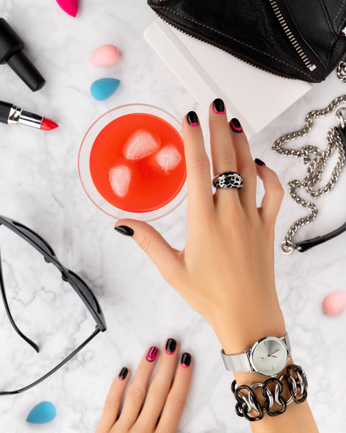 Womans hands with trendy manicure holding cocktail on marble background - Photo, Image