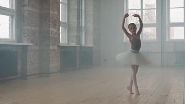 Teljes felvétel gyönyörű és tehetséges 9 éves balerináról tütüben és hegyekben, ahogy kecsesen táncol füsttel teli koreográfia órán. - Felvétel, videó