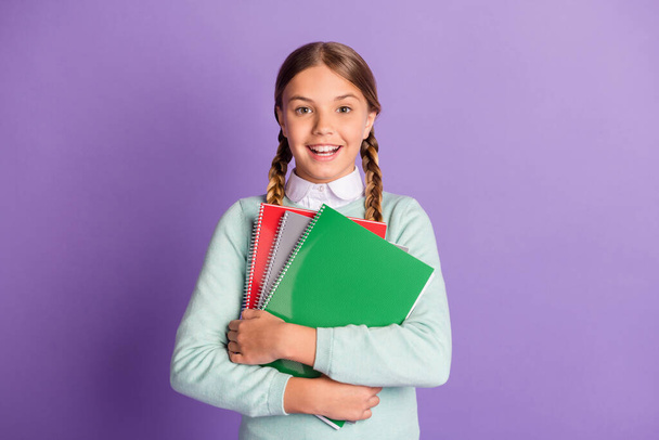 Photo of small excited lady hold pile notebooks look camera wear green sweater isolated violet background - Foto, Imagem