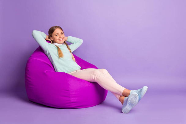 Photo of little lady sit beanbag hands head relax wear green pullover pants shoes isolated violet background - Foto, immagini