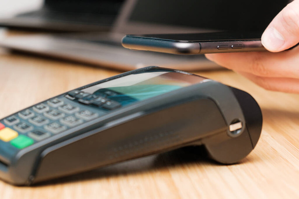 Man uses wireless terminal contactless payment with smartphone - Fotó, kép