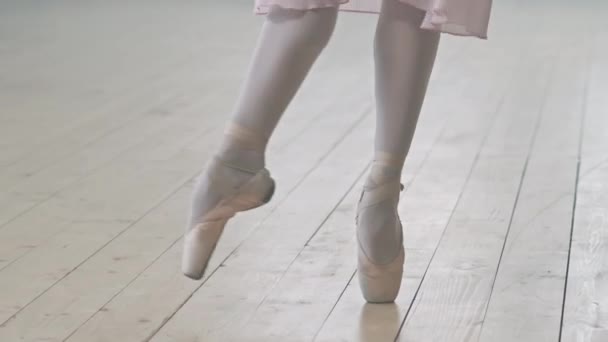 Colpo basso di ballerine irriconoscibili gambe in scarpe da punta balletto ballerino su pavimento in legno in studio di danza - Filmati, video