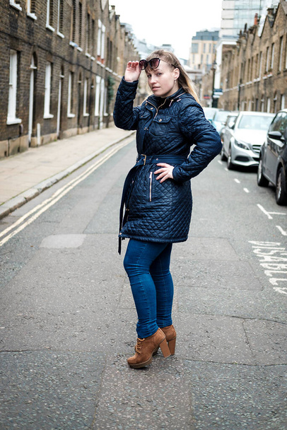 Красива молода жінка стоїть на типовій вулиці Лондона. Вона у сонячних окулярах.. - Фото, зображення