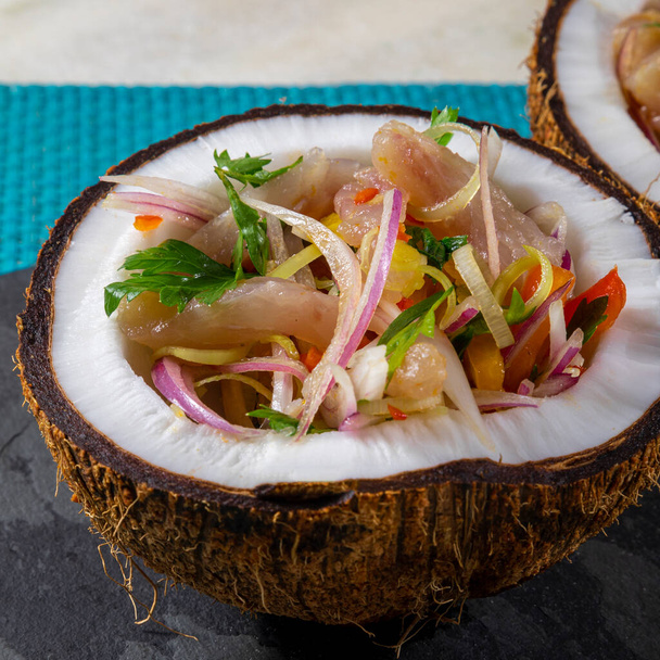 Ceviche dish - appetiser of fresh fish marinated in citrus with tropical fruits served in a Coconut Bowls. - Valokuva, kuva