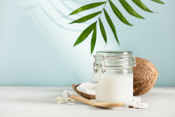 Coconut oil in jar with fresh coconut and tropical leaves, Spa cosmetic and food ingredient, copy space - Φωτογραφία, εικόνα
