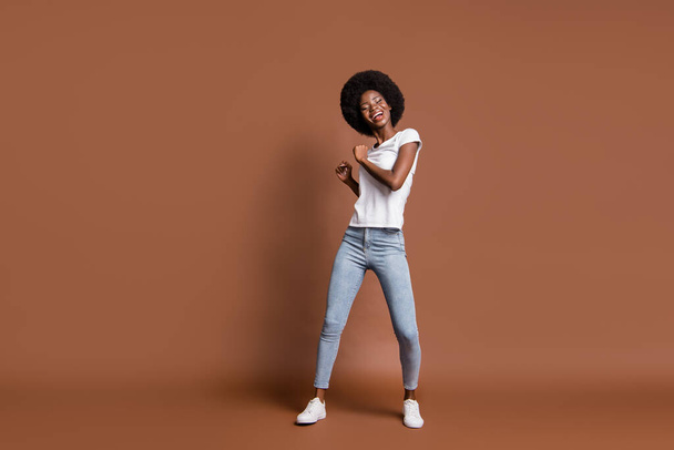 Full size portrait of cheerful dark skin girl enjoy dancing have good mood isolated on brown color background - Fotó, kép