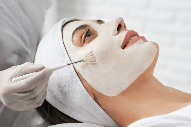Mladá brunetka žena dělá masku v kosmetička. - Fotografie, Obrázek