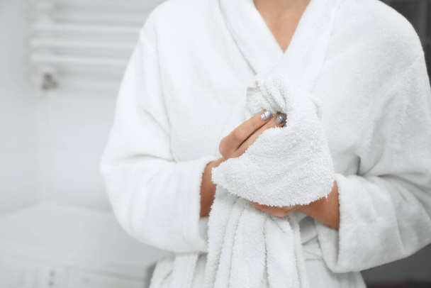 Woman in robe standing in bathroom with white towel.  - Valokuva, kuva