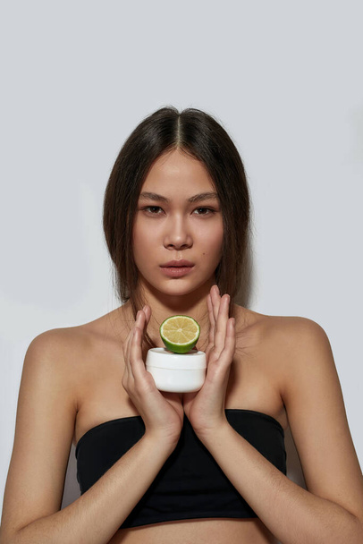 Young asian girl holding half of lemon and cream - Φωτογραφία, εικόνα