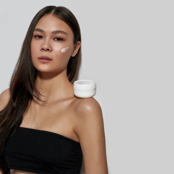 Молодая азиатка с мазком косметологического крема - Фото, изображение